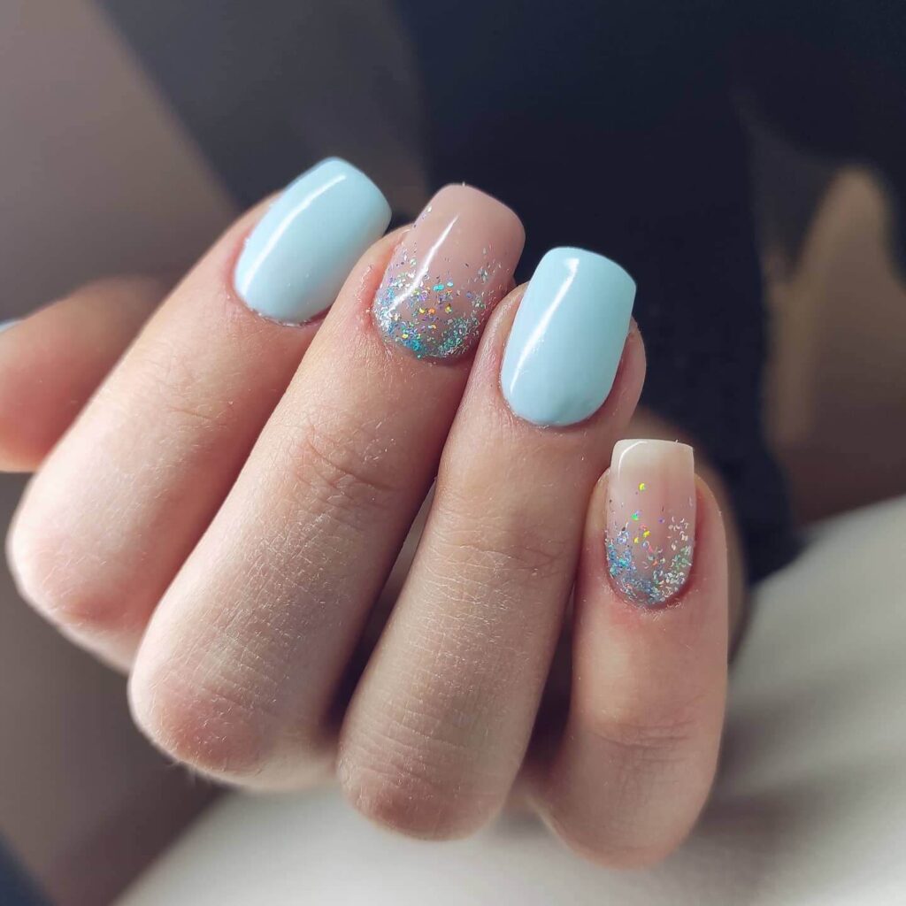 A collection of light blue nails with ombre nail designs, glitter accents, and unique floral patterns showcasing creativity and style.