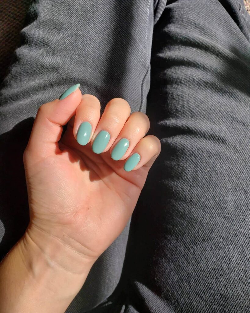 Freshly painted sage green nails with a minimalist design. This muted green nail polish trend is perfect for a subtle, nature-inspired manicure.