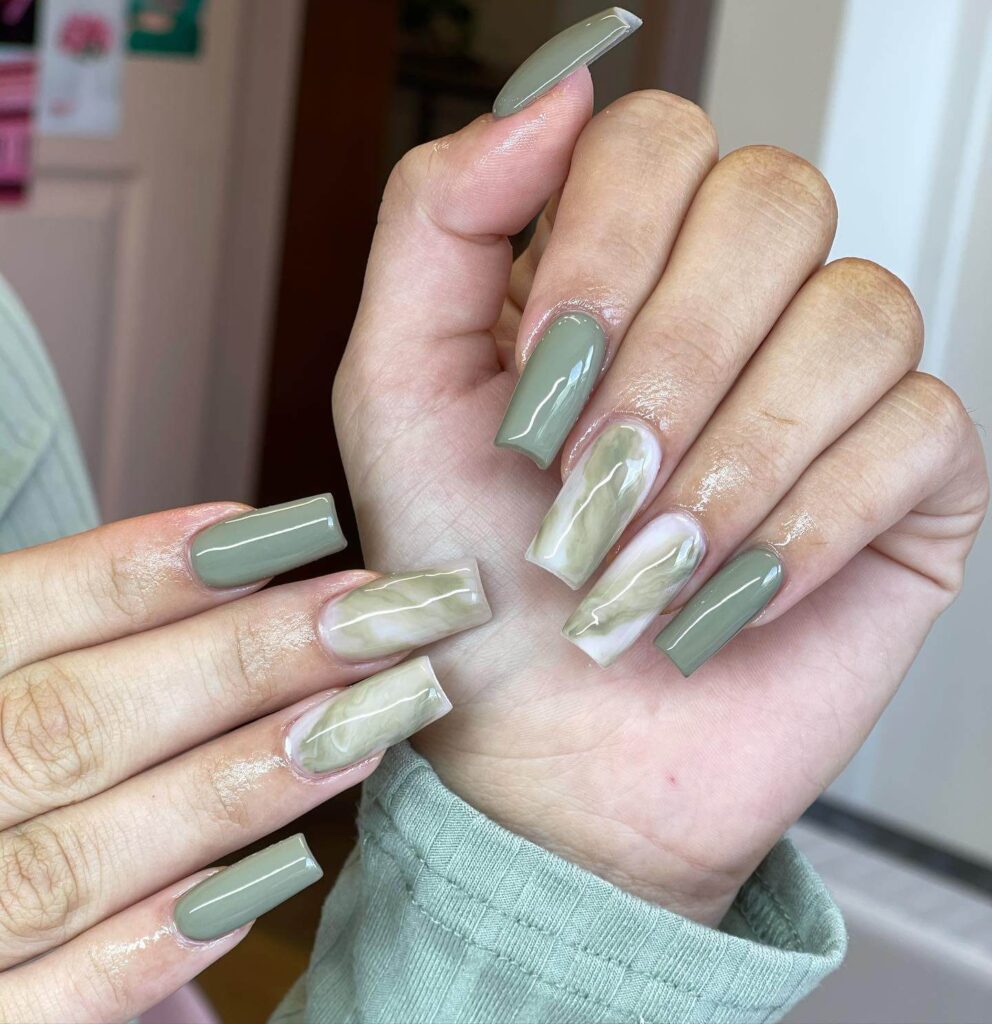 Freshly painted sage green nails with a minimalist design. This muted green nail polish trend is perfect for a subtle, nature-inspired manicure.